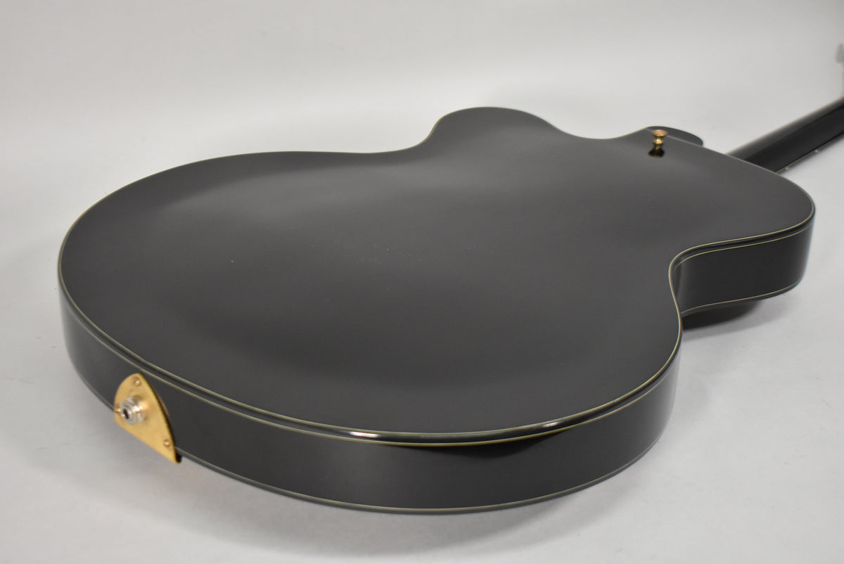 The guitar's black back and sides are visible from the lower bout, with a gold output jack plate and strap button.