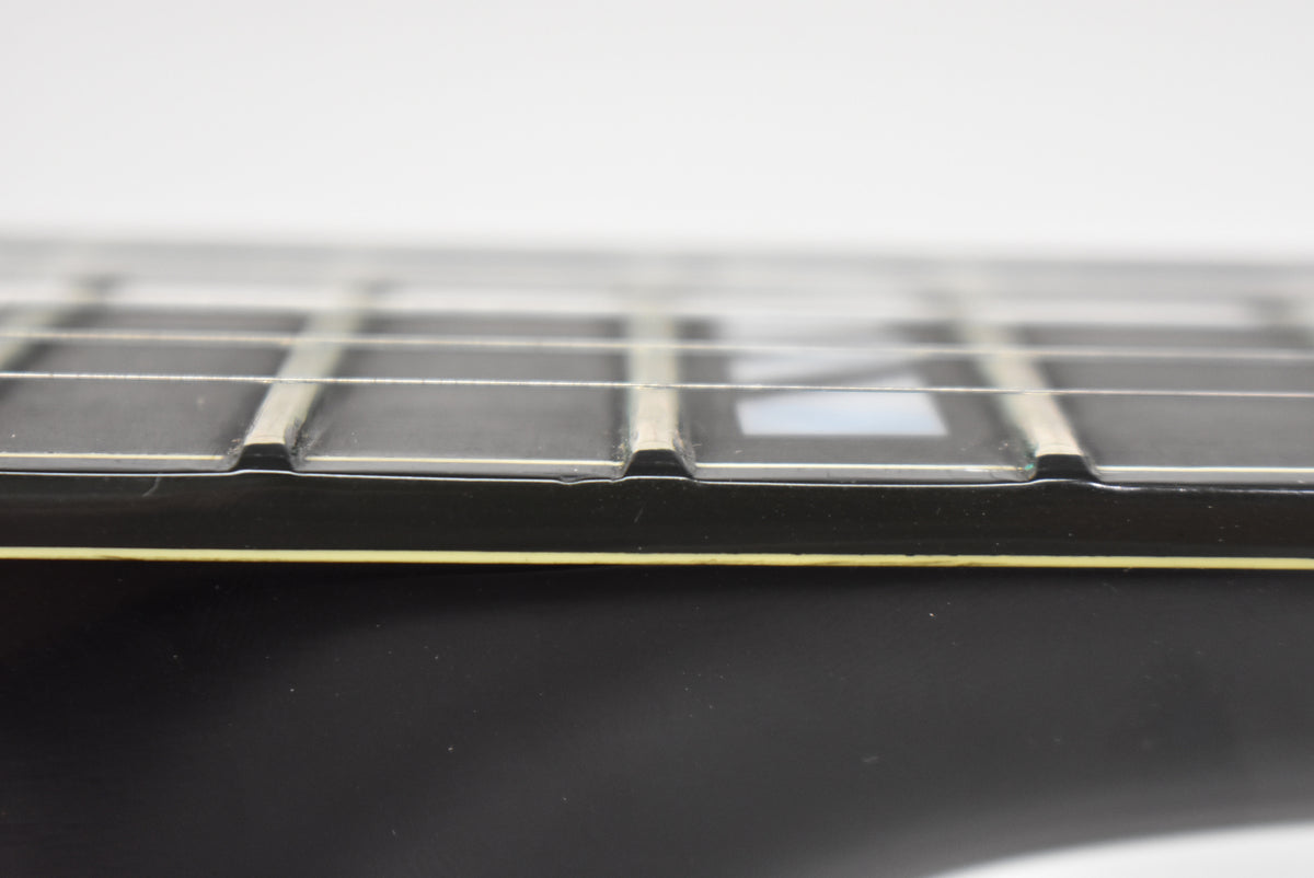 Close-up of the guitar's black fretboard and frets, showing light wear and a rectangular mother-of-pearl inlay.