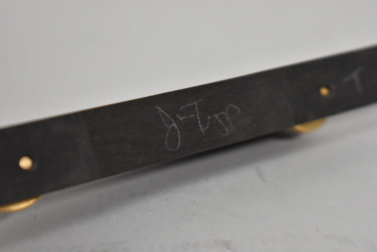 The guitar's black headstock edge is angled, showing a white signature and gold tuner posts with light wear.