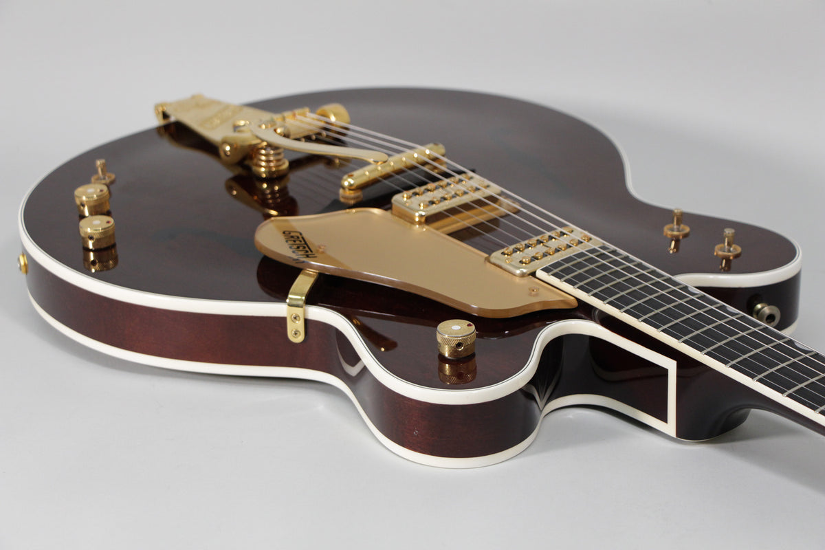 A dark cherry hollow-body electric guitar with gold hardware and white binding, viewed from the upper bout towards the neck.