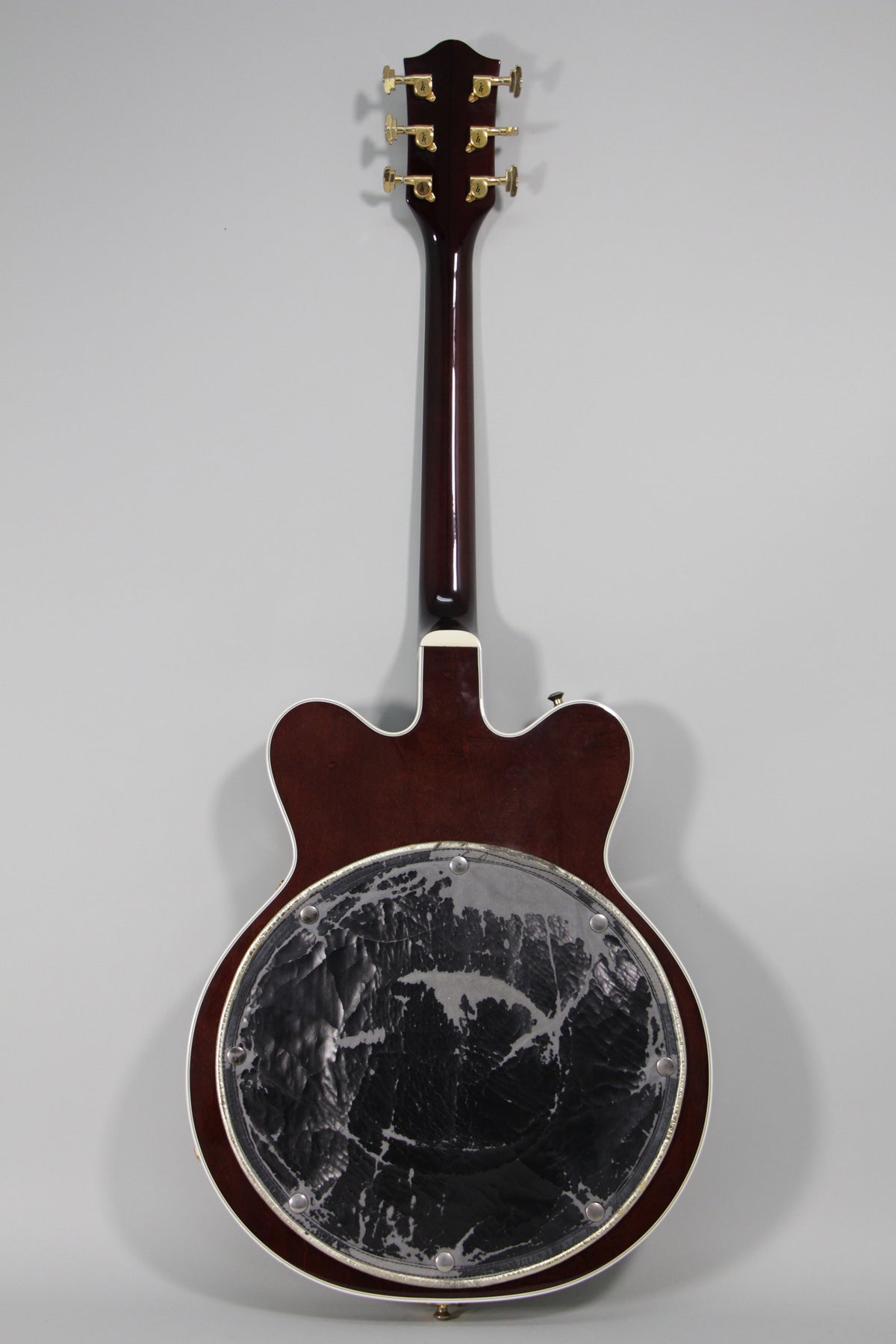 Full rear view of a dark cherry hollow body guitar with gold tuners and a heavily worn black back pad.