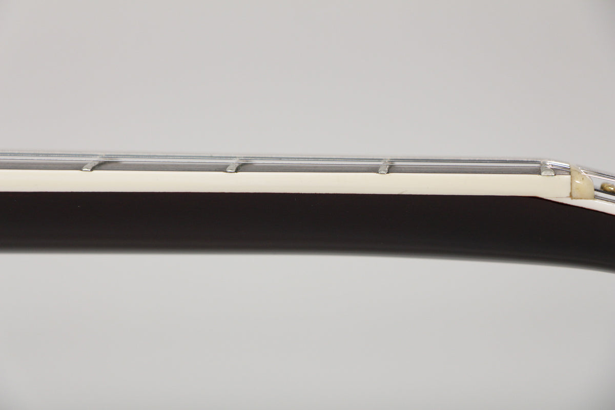 Close-up of the guitar's dark brown neck, showing the cream binding, frets, and nut from a side angle.