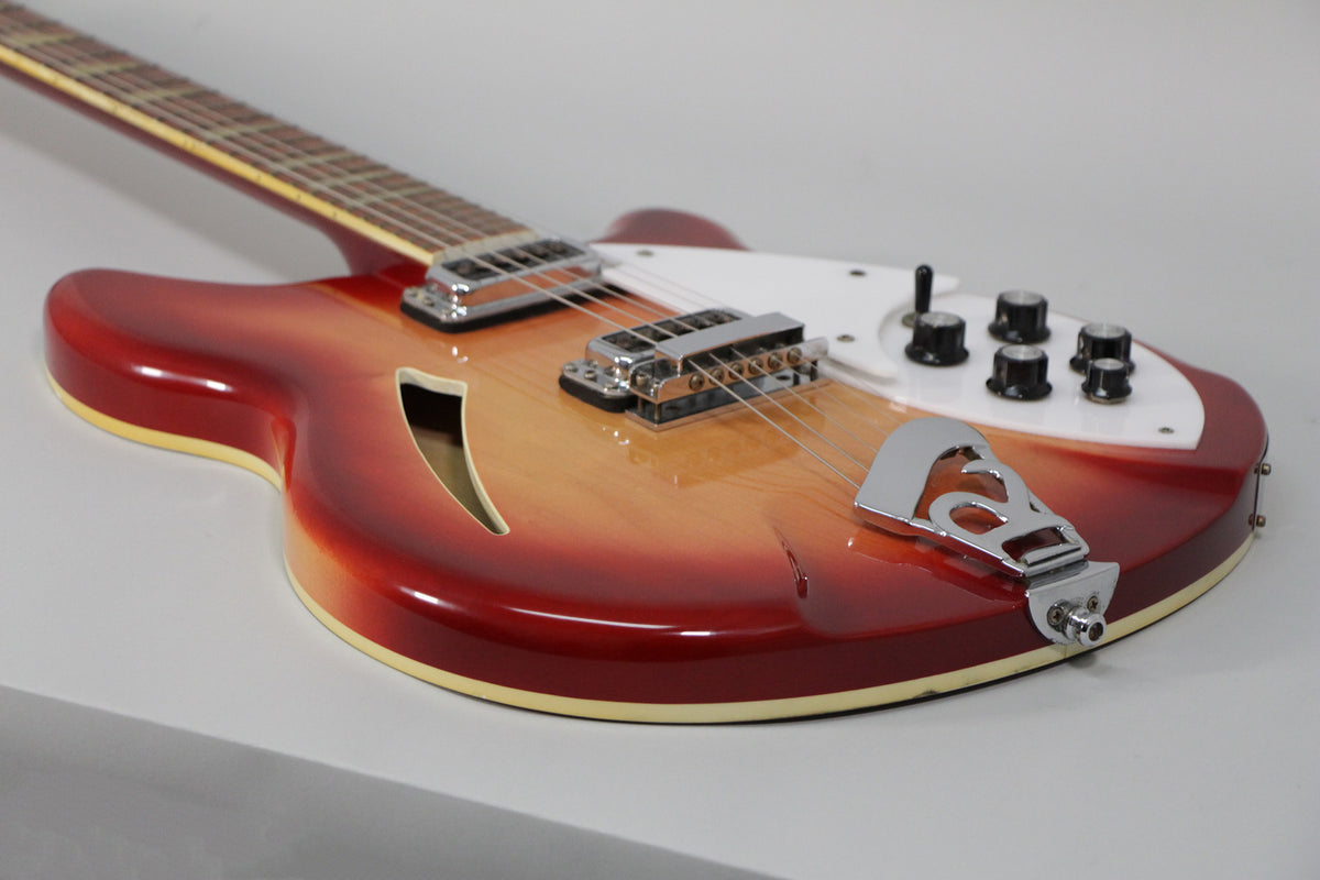 The Fireglo semi-hollow guitar, angled from the neck, shows its F-hole, white pickguard, chrome hardware, and black control knobs.