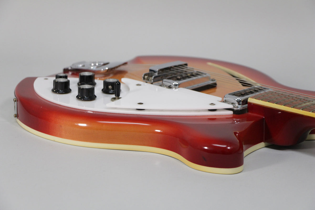 The Fireglo guitar body, with a white pickguard and four black control knobs, is angled from the lower left.