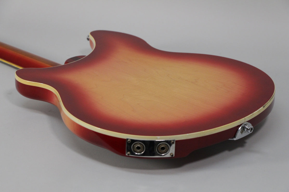 The guitar's Fireglo back, with a light center fading to dark red, shows two output jacks and a strap button on the lower edge.