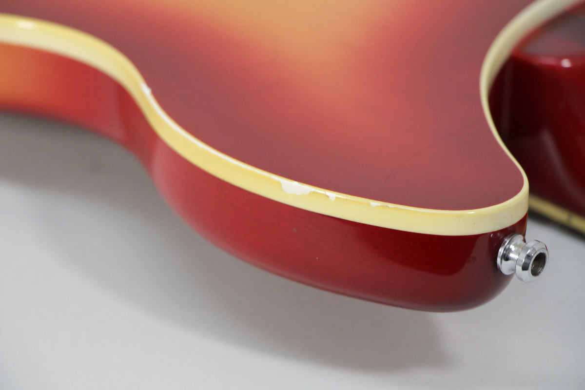 Close-up of the guitar's lower bout, showing the Fireglo finish and cream binding with several chips near the chrome output jack.