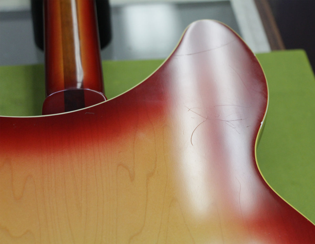 Close-up of the guitar's upper bout and neck heel, showing the Fireglo finish with several visible scratches and finish checking.