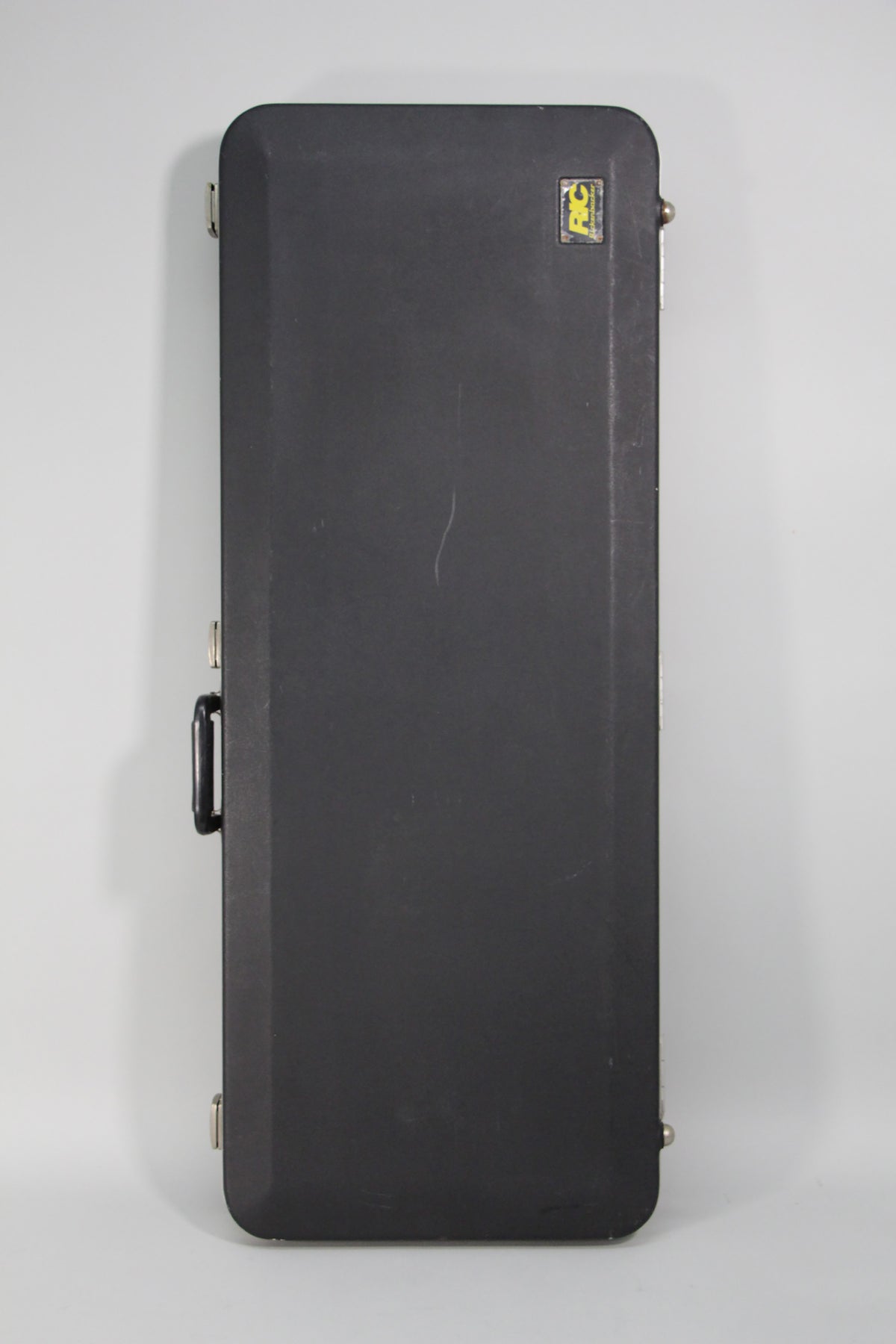 The guitar's black hard case is shown from above, with a handle and three silver latches visible, and light scuffs on its surface.
