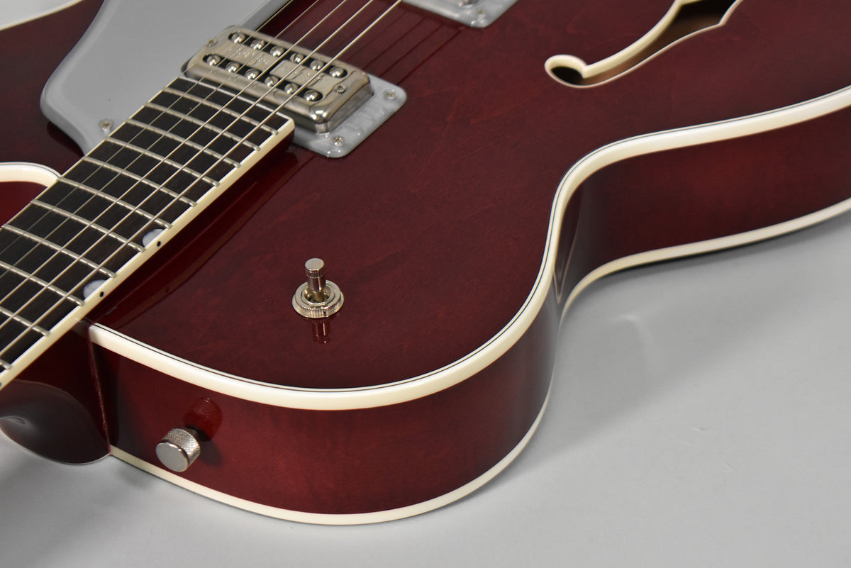 Close-up of the cherry stain body, showing the lower bout, F-hole, pickup selector, and strap button.