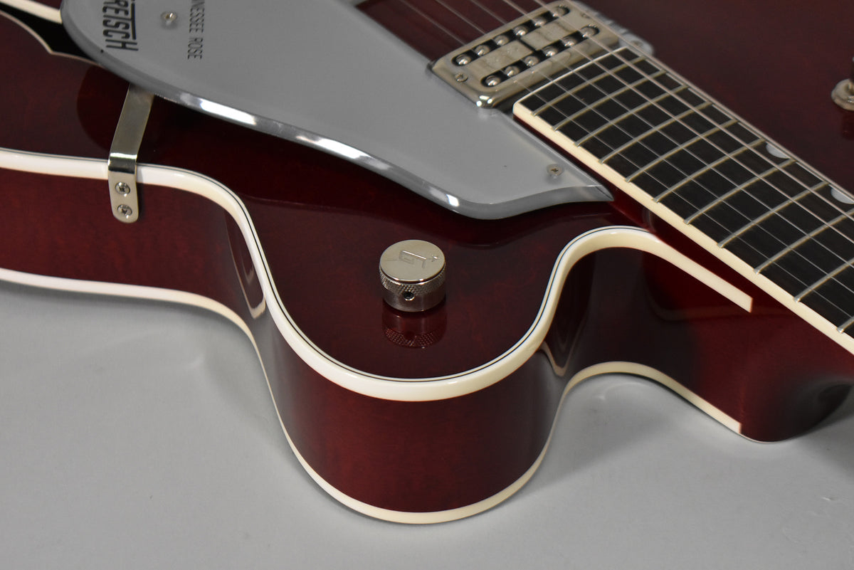 Close-up of the cherry-stained guitar body's lower bout, showing a chrome knob, white binding, and part of the pickguard and fretboard.