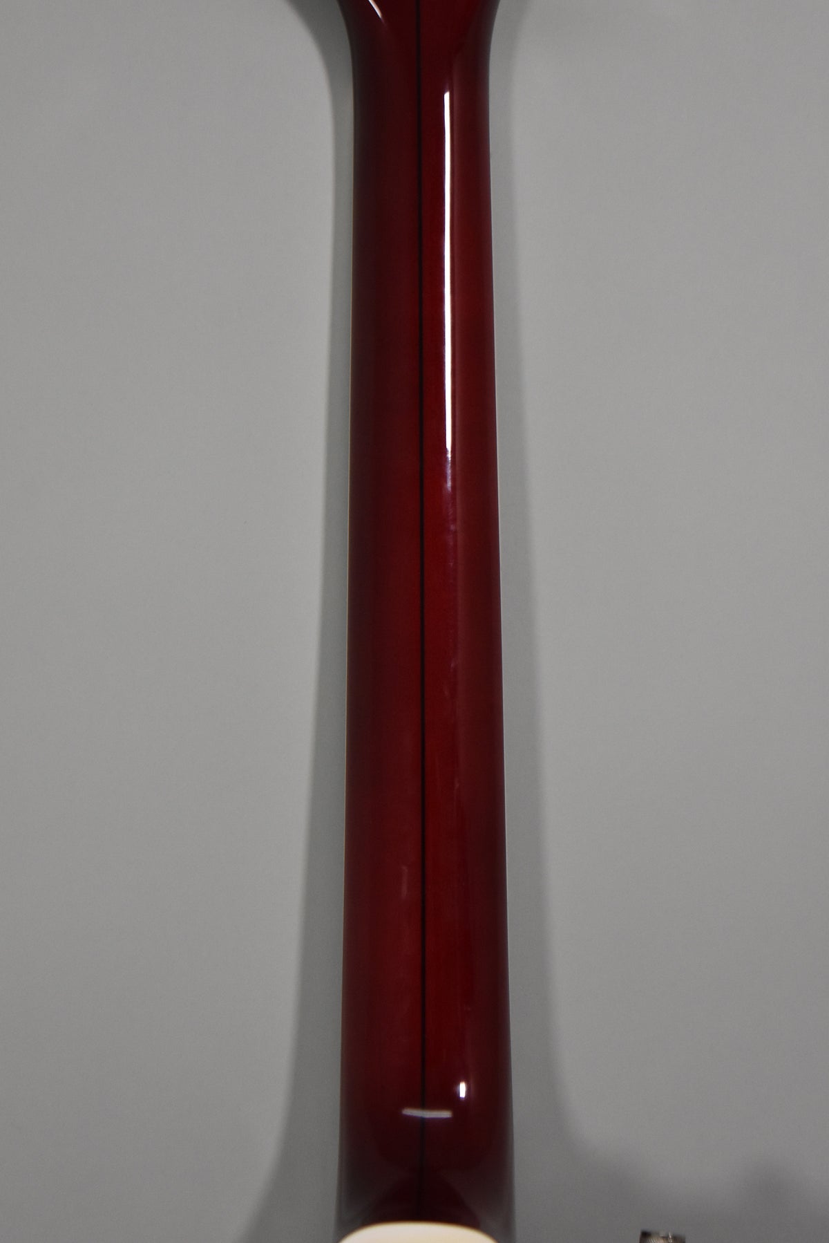 The guitar's cherry-stained neck, with a dark center stripe, is shown from the back, tapering towards the headstock.