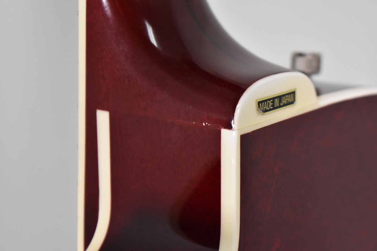Close-up of the cherry stain guitar neck heel, showing cream binding, a "MADE IN JAPAN" plate, and minor finish wear.