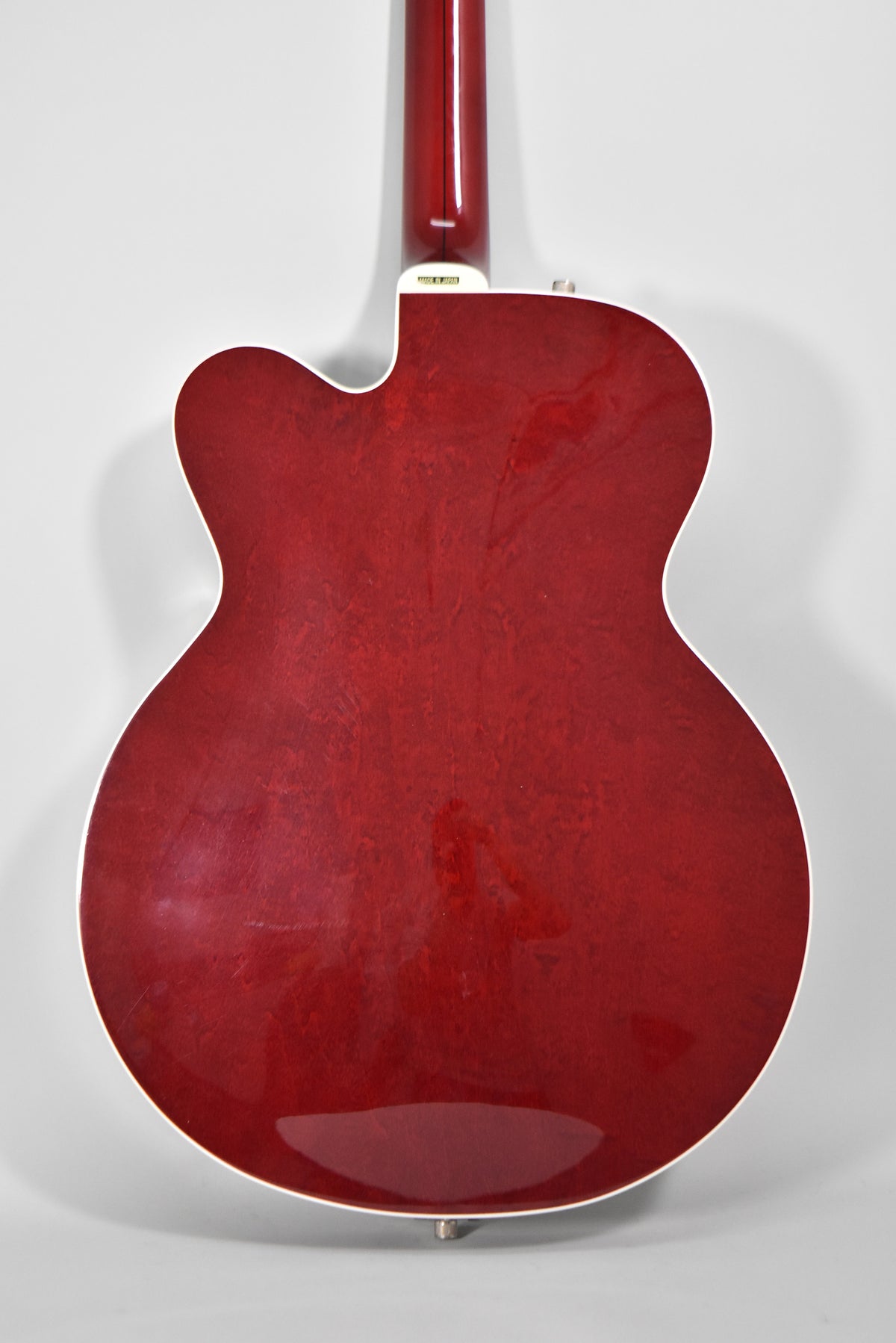 The back of a cherry stain hollow-body electric guitar, showing the neck joint and a few light scratches on the body.