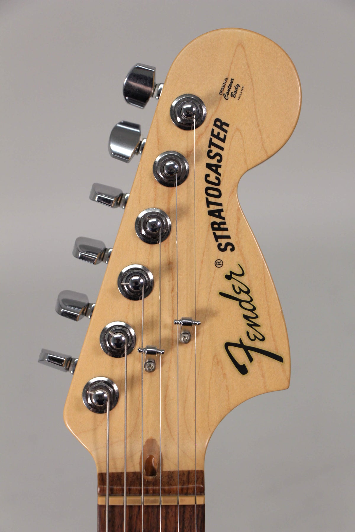 Close-up of the light maple headstock with chrome tuners, string trees, and a dark rosewood nut, showing light wear.