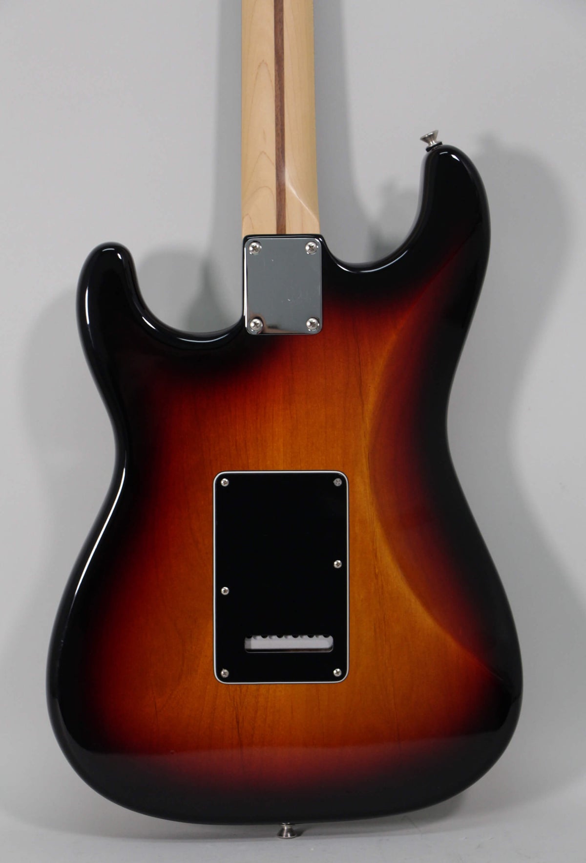 The guitar's sunburst back shows a black tremolo cavity cover and a four-bolt chrome neck plate, with a light maple neck.
