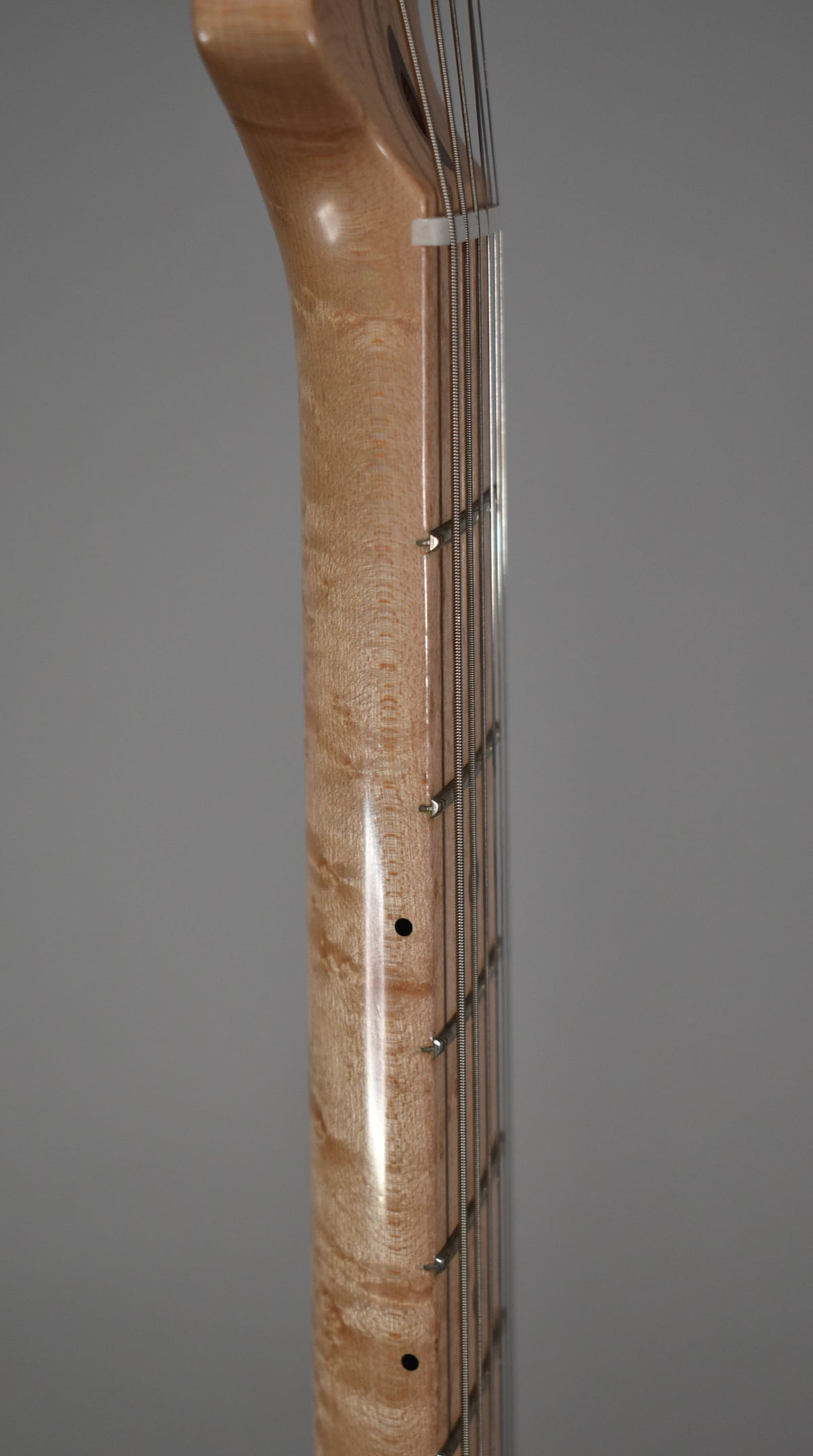 Close-up of the guitar's birdseye maple neck and fretboard, showing the light wood grain and metal frets.
