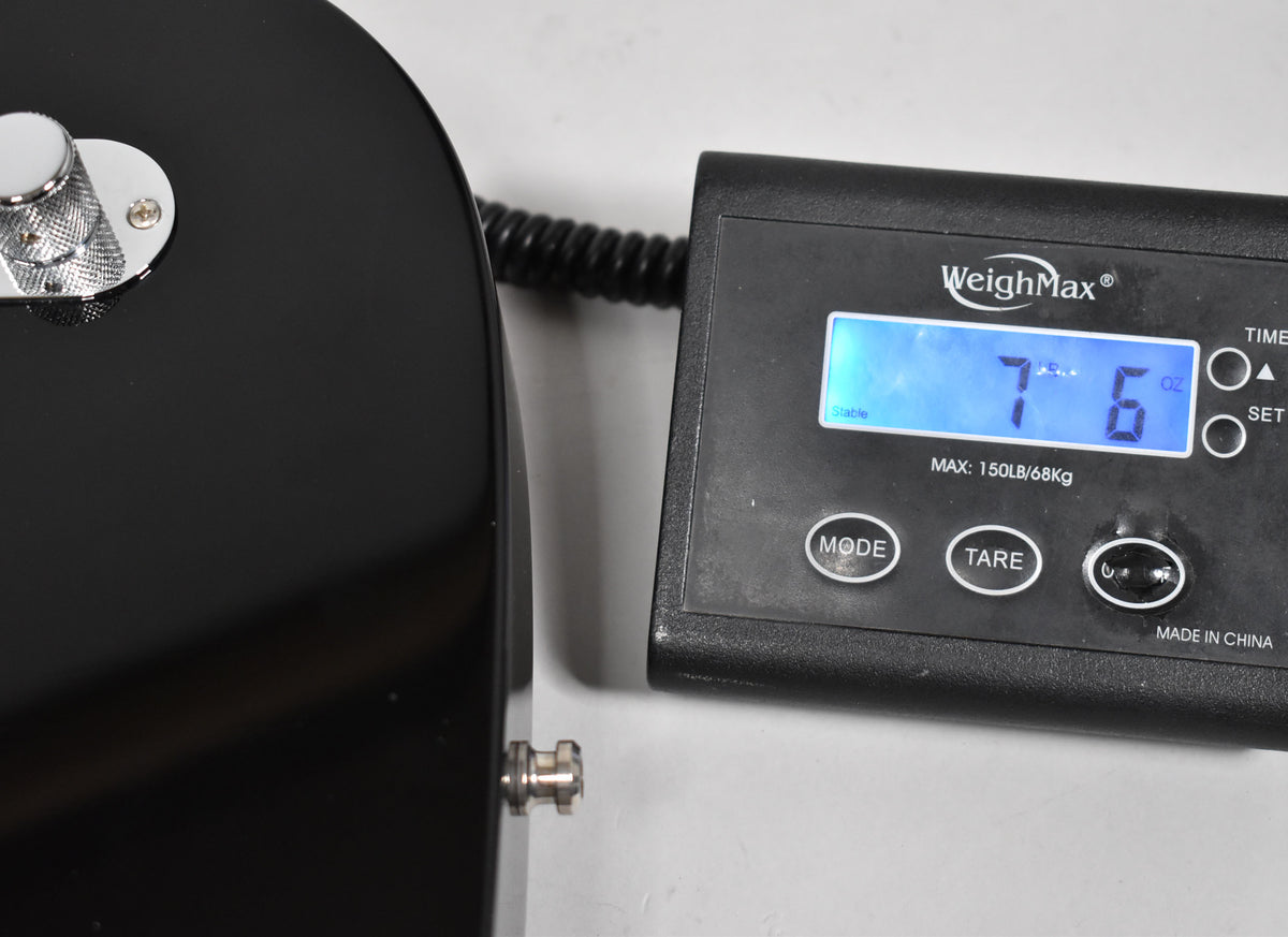 The black guitar body's lower bout and output jack are next to a digital scale displaying "7 lbs 6 oz".