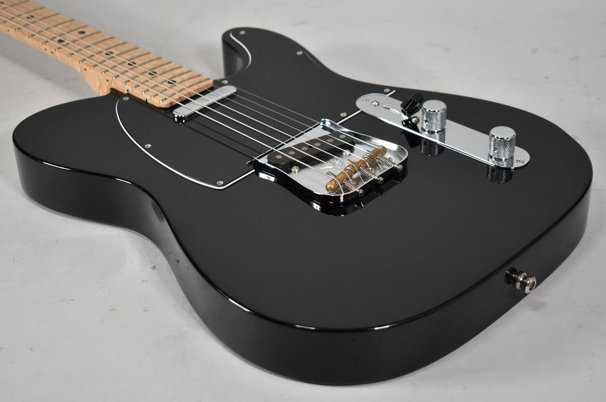 Angled view of a glossy black Telecaster body with a black pickguard, chrome bridge, control plate, and knurled knobs.