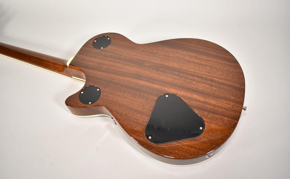 The back of a glossy dark brown guitar with visible wood grain, showing two round and one triangular black control plate.