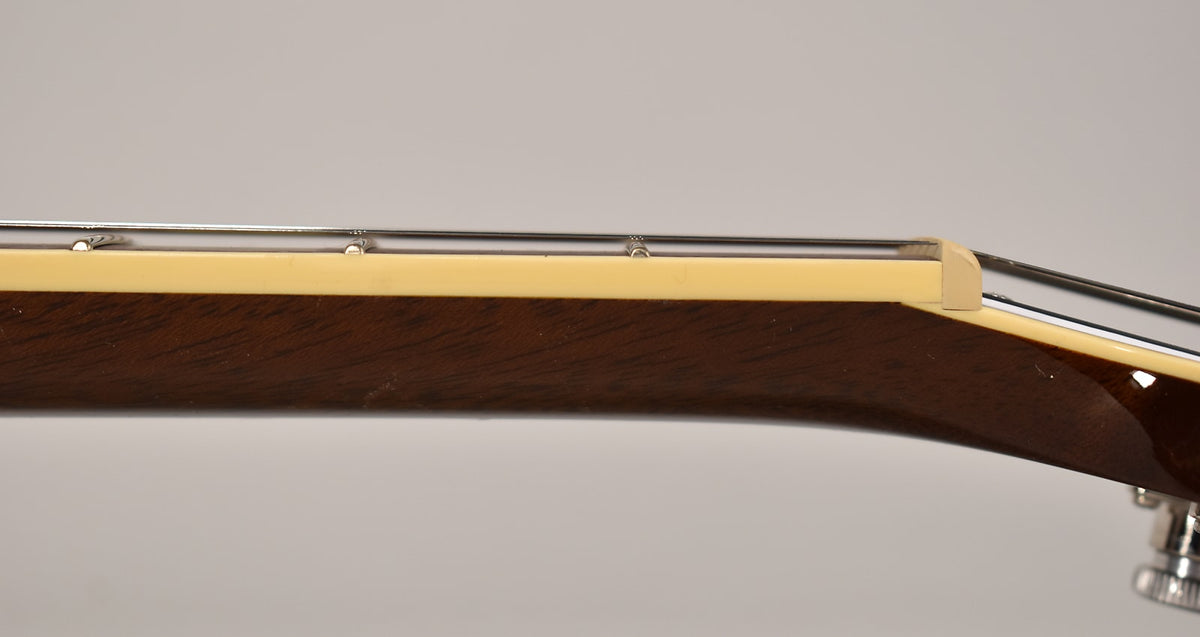 Close-up of the guitar's dark brown neck, showing the cream binding, nut, and the first few frets with minor wear.