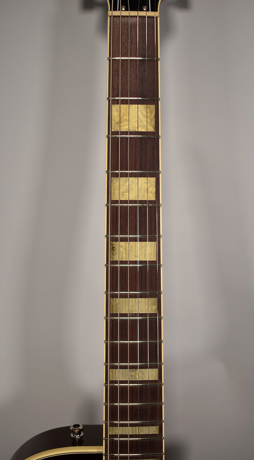 Close-up of the dark rosewood fretboard with rectangular pearloid block inlays, cream binding, and nickel frets.