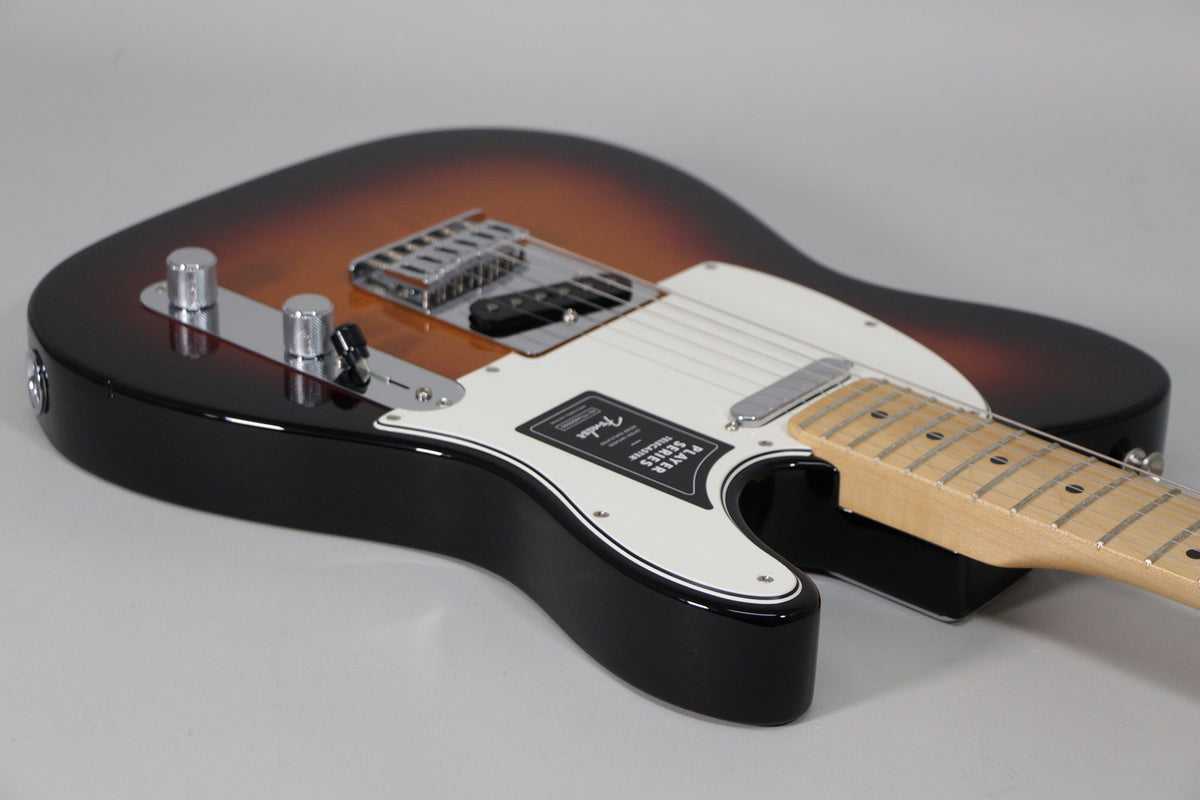 The Telecaster's glossy sunburst body and white pickguard are seen from the lower bout, revealing chrome hardware and a maple neck.
