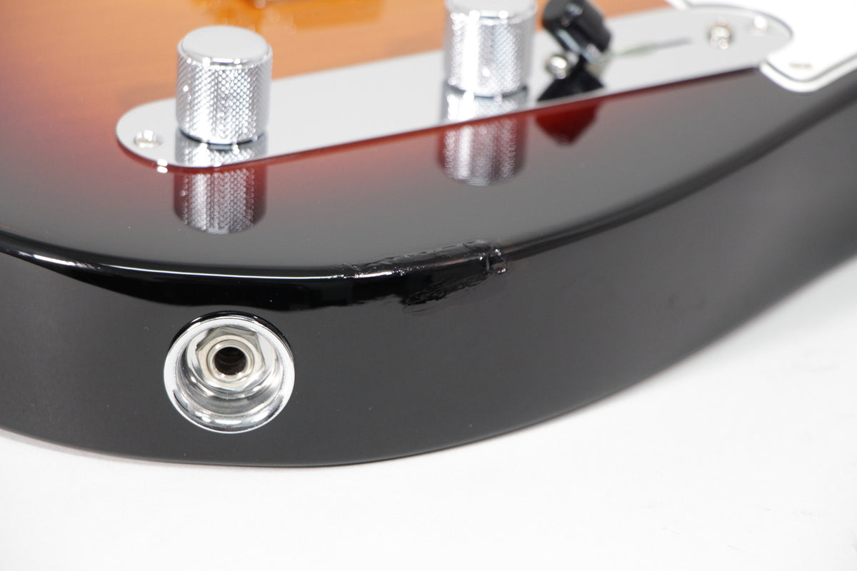 Close-up of the guitar's lower bout, showing the chrome output jack and a small chip in the glossy black finish near the strap button.