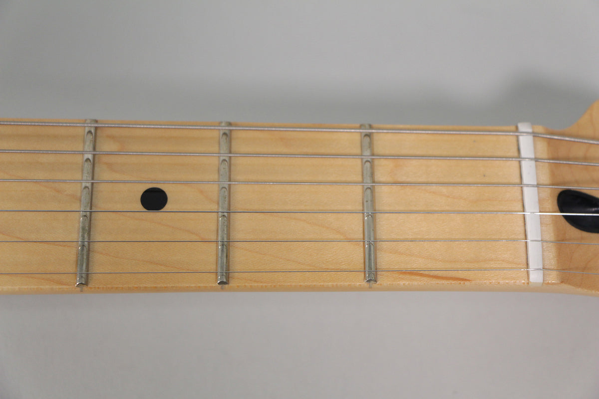Close-up of the maple fretboard from the nut to the 5th fret, showing a black dot inlay at the 3rd fret.