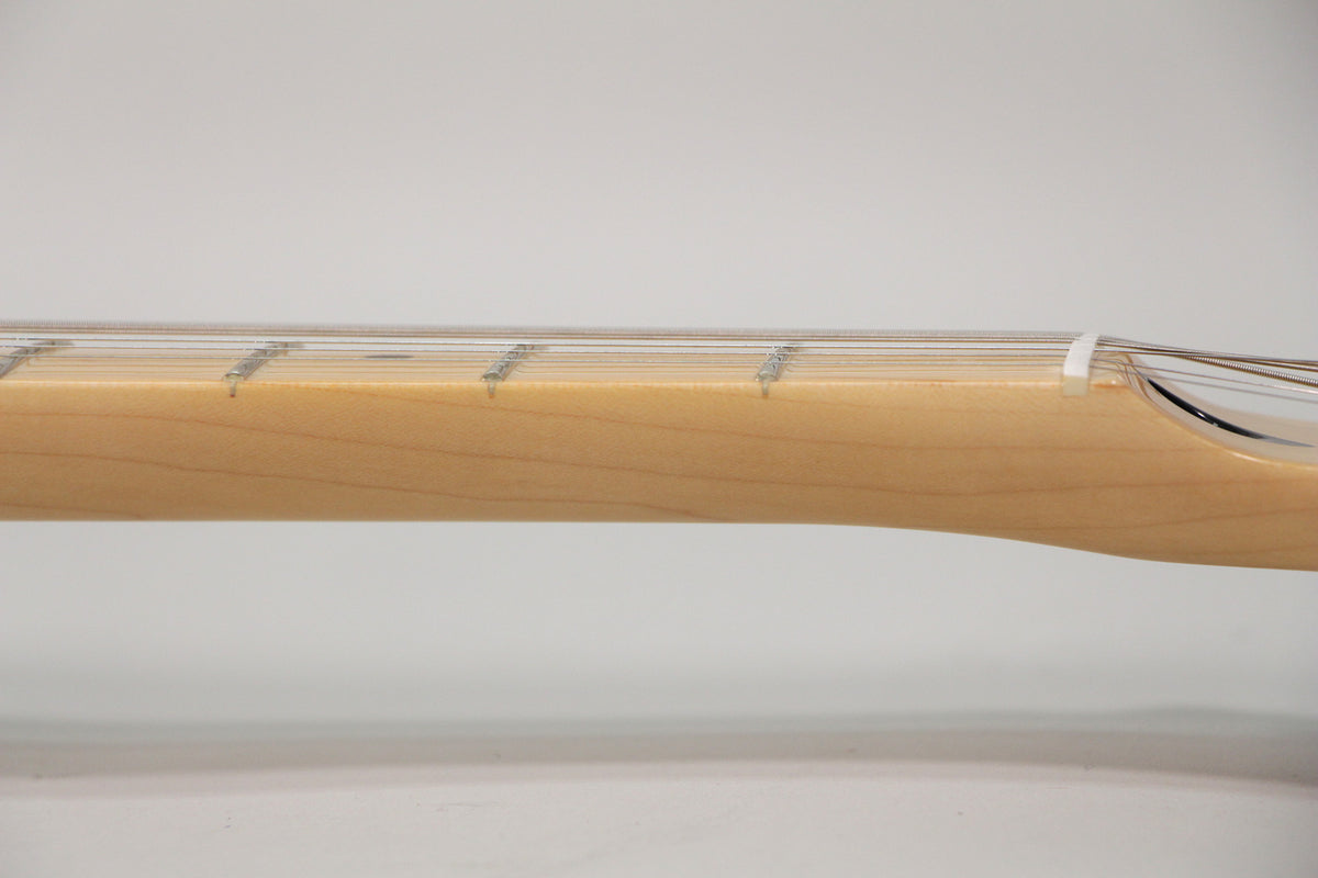 Close-up of the light maple neck and fretboard, showing the first few frets and the white nut.