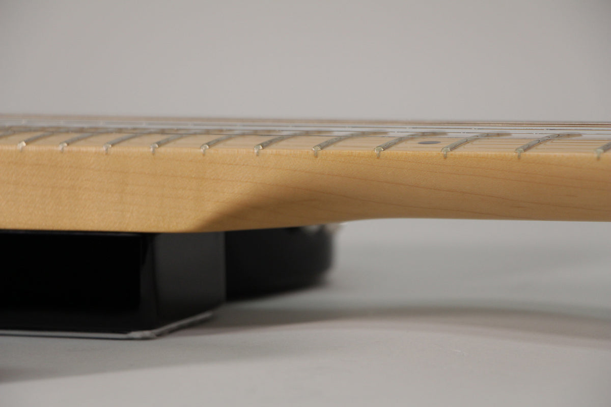 Close-up of the guitar's light maple neck and fretboard, showing the frets and strings from a side angle, with a dark body below.
