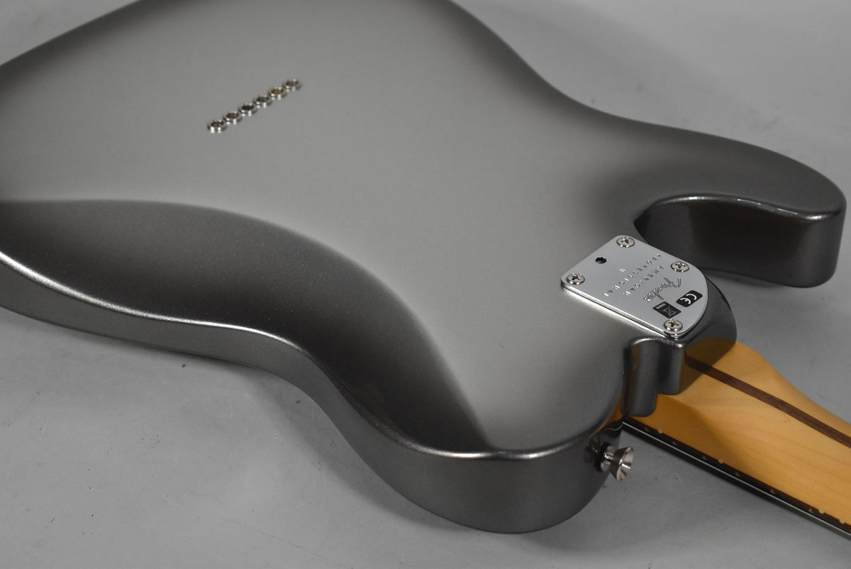 The back of the metallic gray guitar body is angled, showing the chrome neck plate, strap button, and six string ferrules.