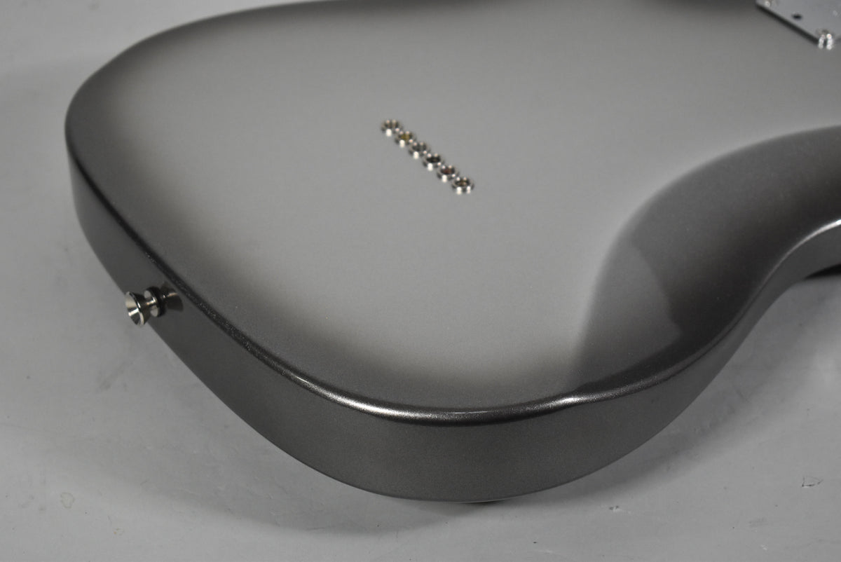 The guitar's back, in a metallic silver-grey finish, shows six string ferrules and a strap button on the lower bout.