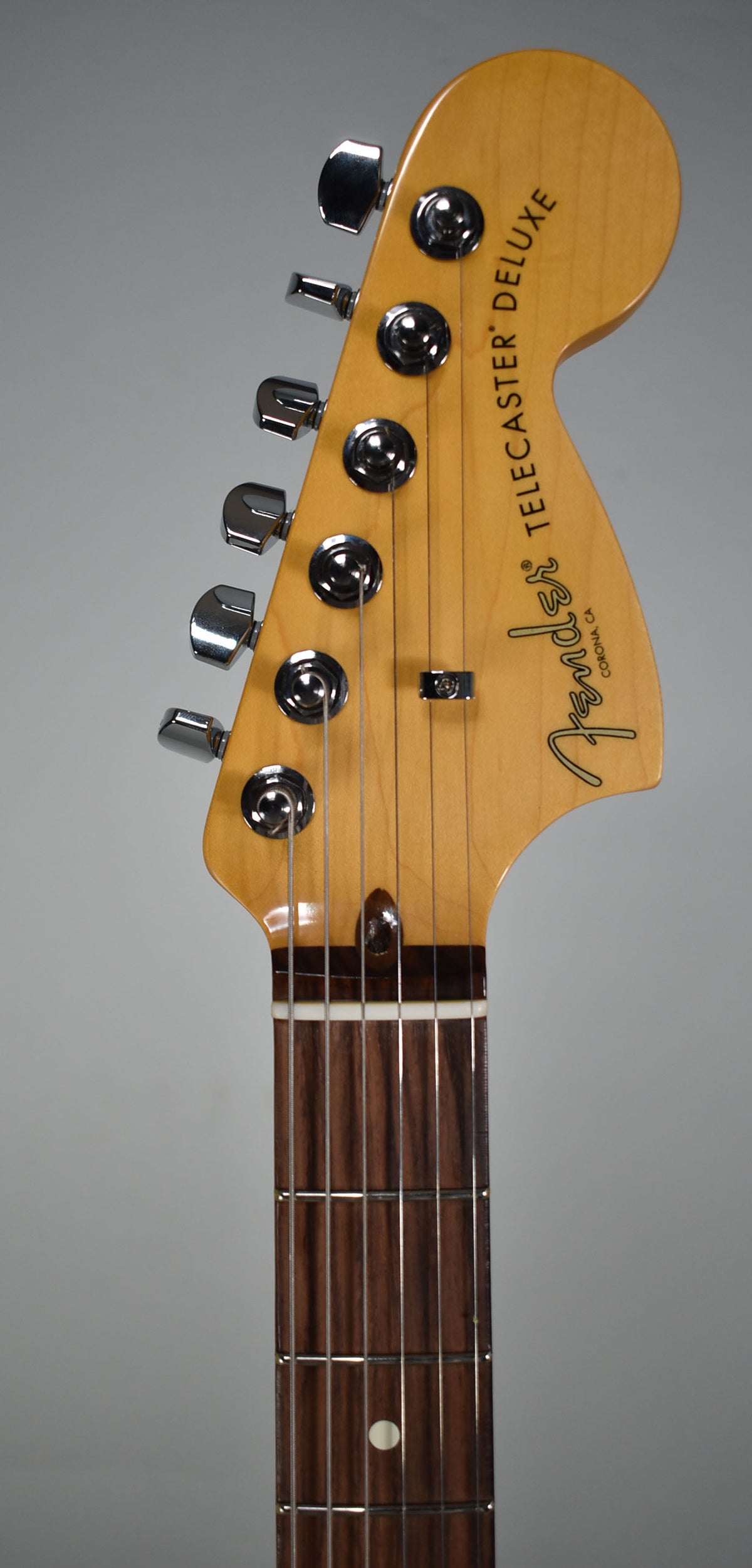 Close-up of the guitar's headstock and upper fretboard, showing six chrome tuners, a string tree, and a dark rosewood fretboard.