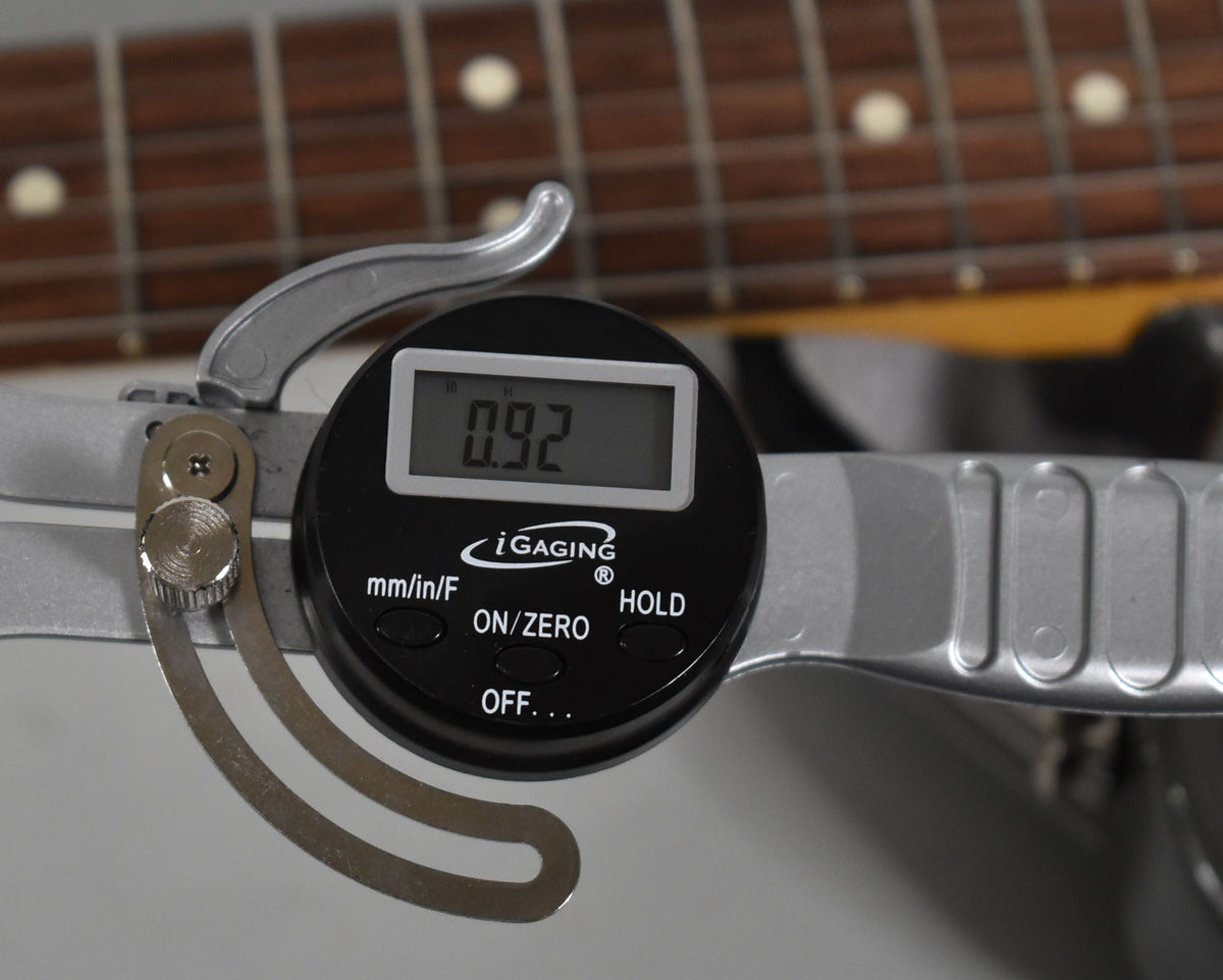 Close-up of the guitar's fretboard with a digital caliper measuring fret height at 0.92mm, showing the dark rosewood and dot inlays.