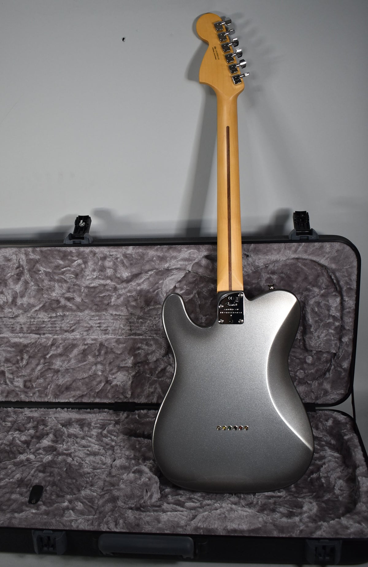 Full rear view of a metallic silver Telecaster with a maple neck, resting in a grey plush-lined hard case.