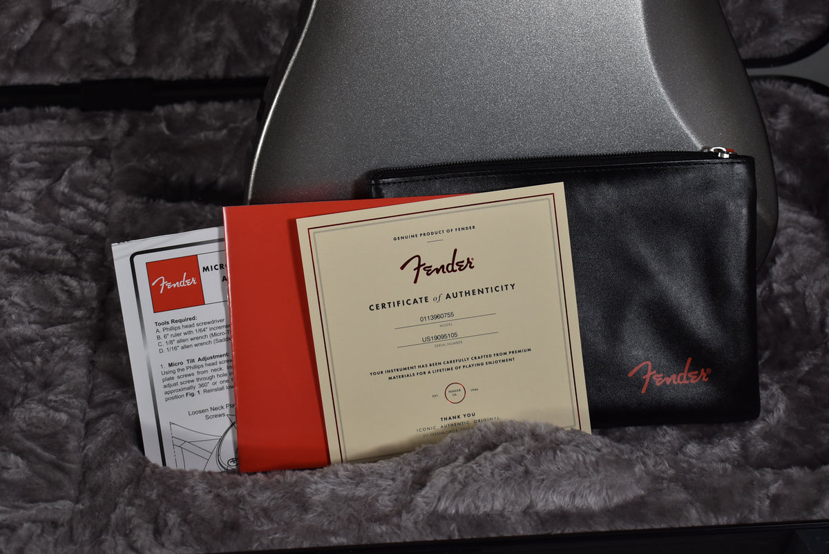Close-up of the guitar's accessories, including a certificate of authenticity, manual, and black pouch, resting in the plush case.