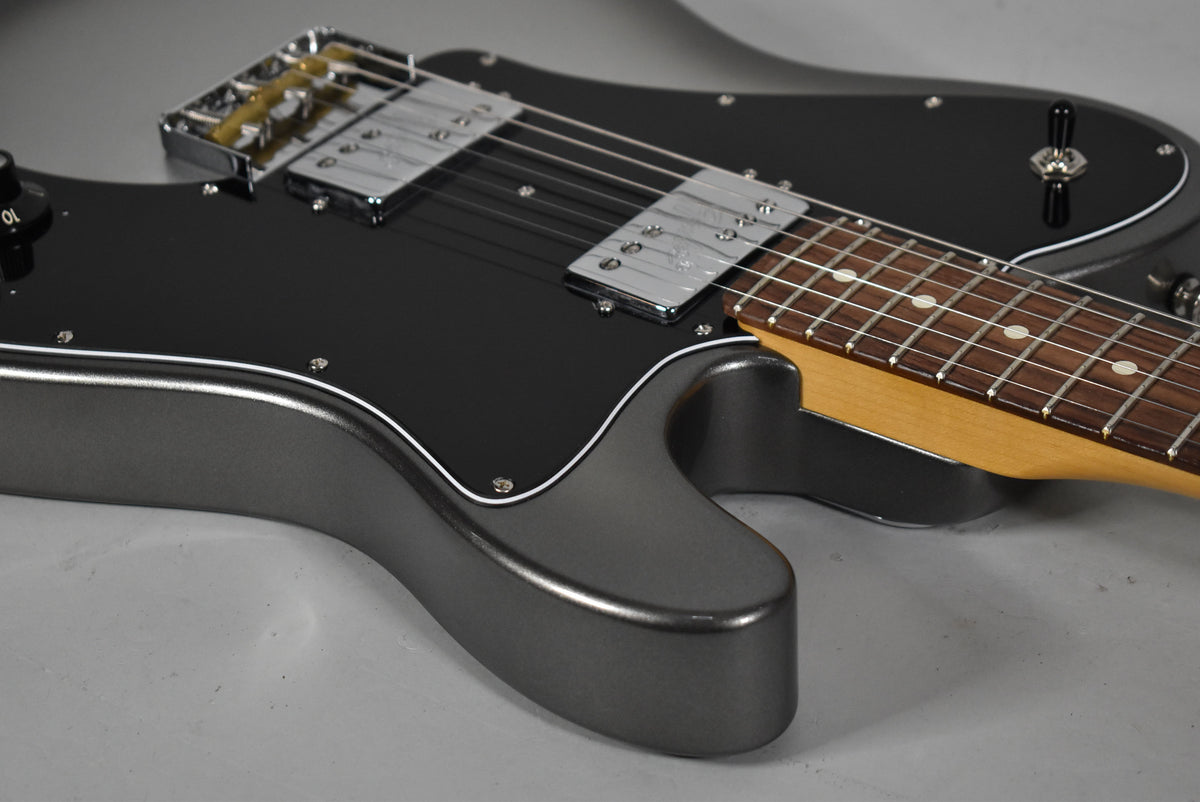 The upper body of a metallic grey guitar, with a black pickguard, two chrome humbuckers, and a maple neck.