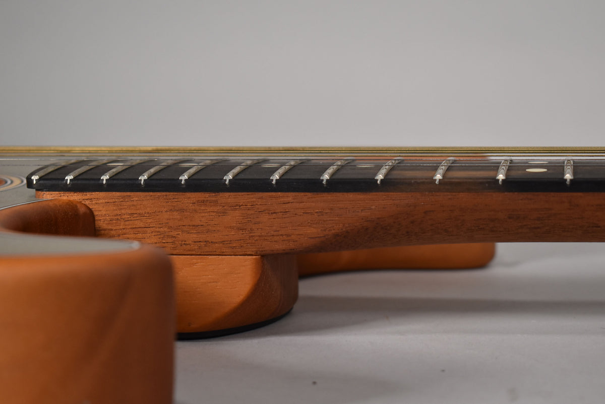 Close-up of the guitar's dark fretboard and light brown neck, viewed from the side, showing frets and strings.