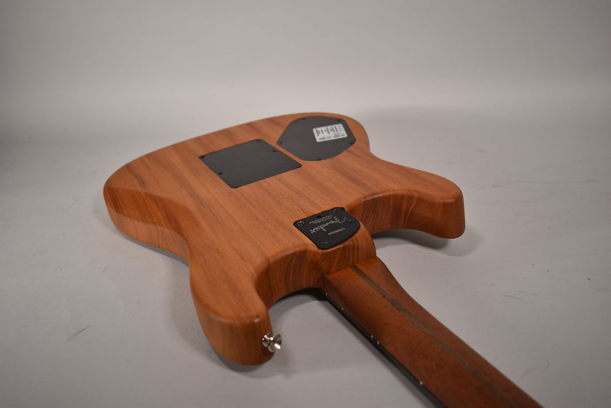 The guitar's back, angled from the lower bout, shows a natural wood finish, two black control plates, and a neck plate.
