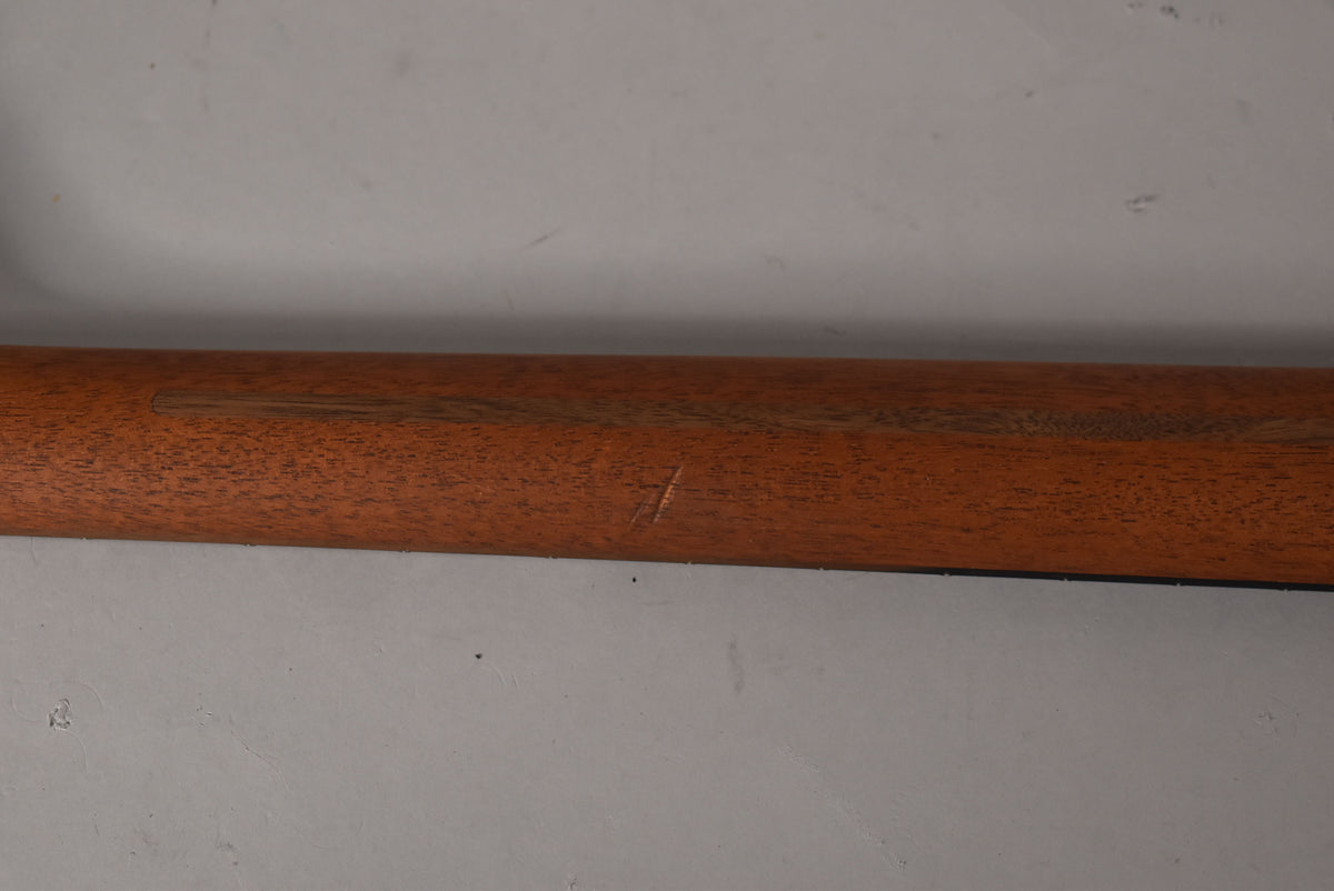 Close-up of the guitar's neck, showing a light brown wood finish with a few visible scratches and a darker wood grain running lengthwise.