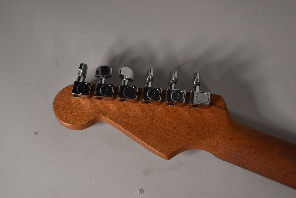 The back of the guitar's headstock and neck, showing six chrome tuning machines on a reddish-brown wood finish.