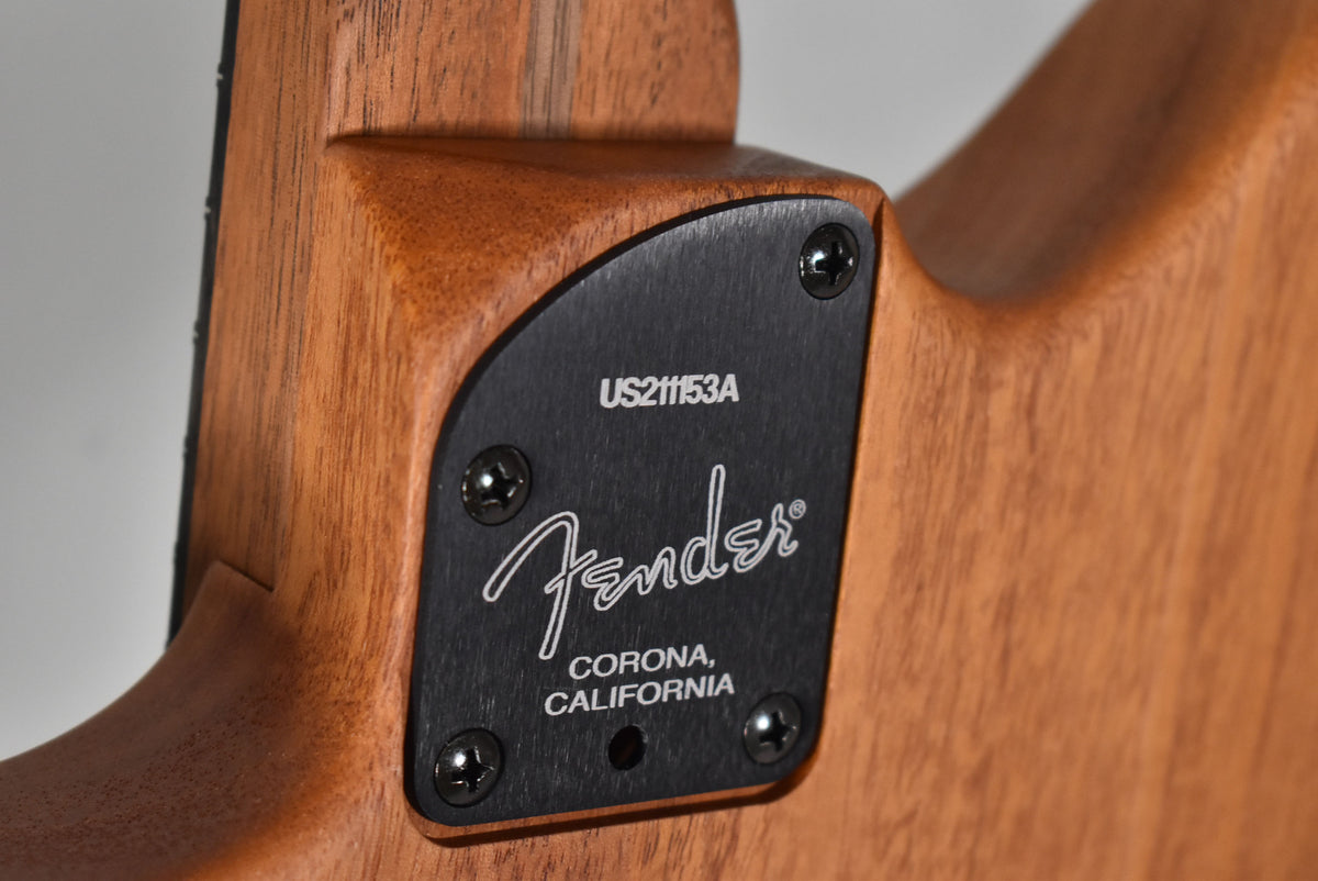 Close-up of the guitar's neck joint, showing a black metal plate with four screws and a serial number on the natural wood finish.