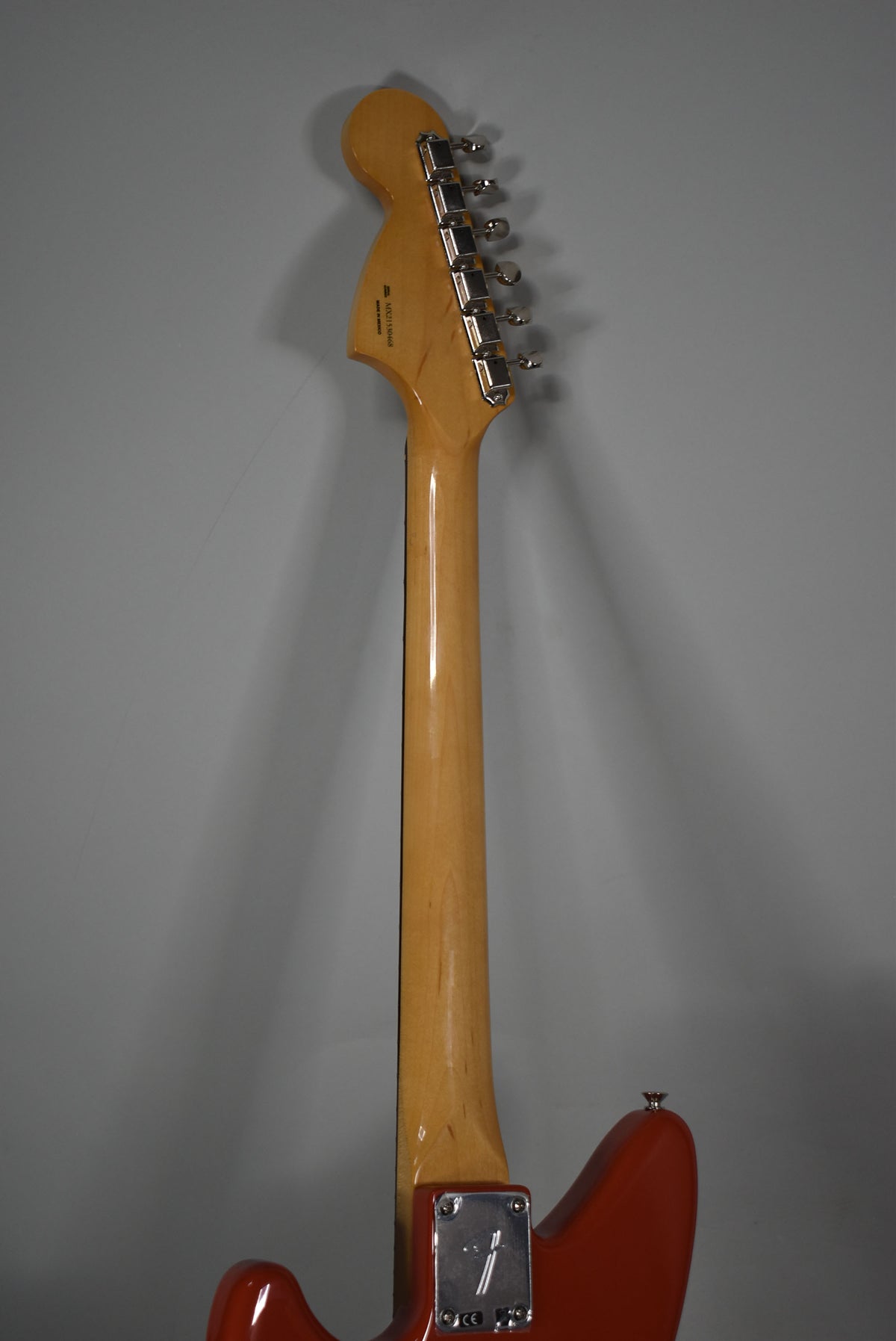The guitar's maple neck and headstock are viewed from behind, with six chrome tuners and a four-bolt neck plate visible.
