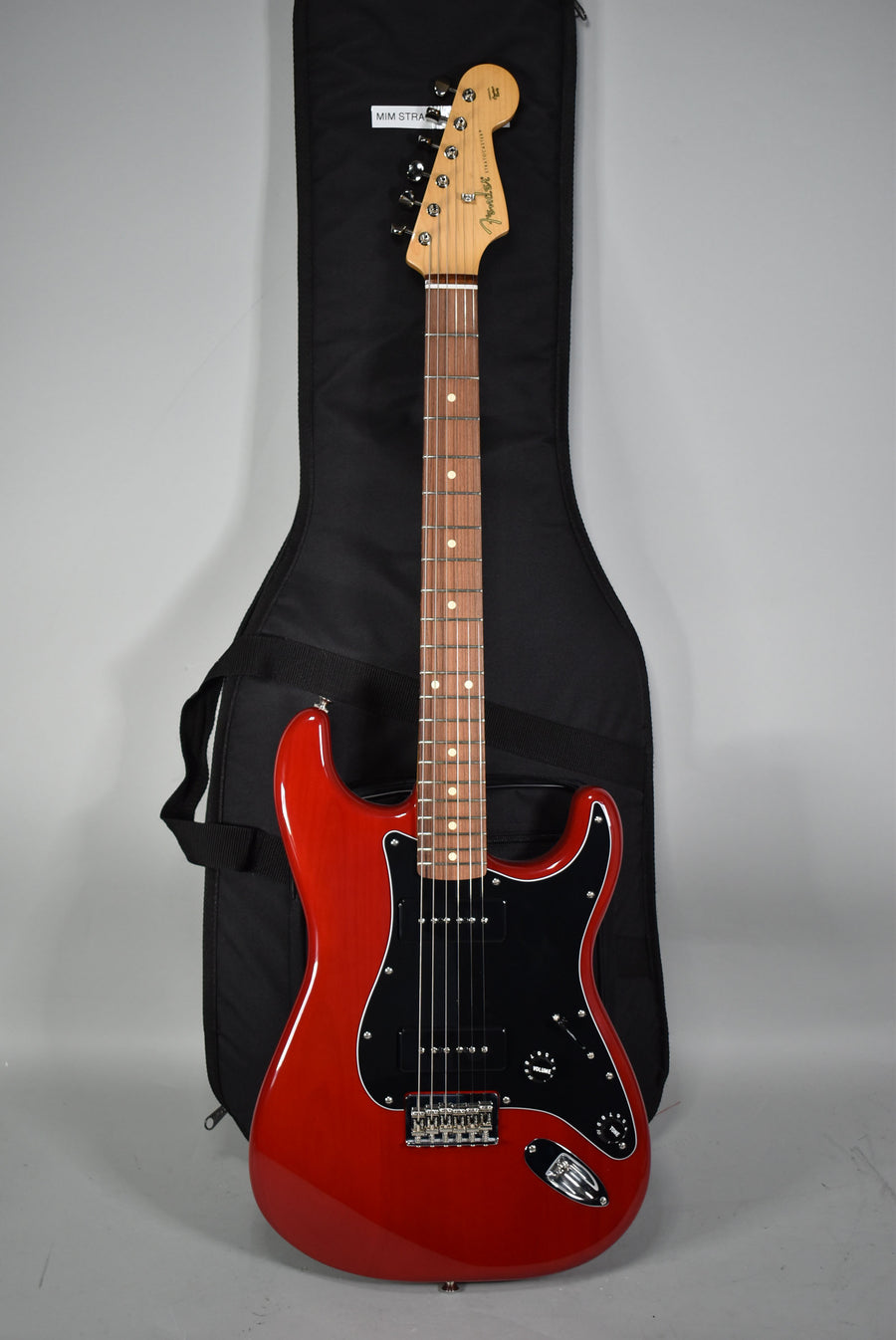 Full view of a glossy crimson red electric guitar with a black pickguard, three black P90 pickups, and a maple neck.