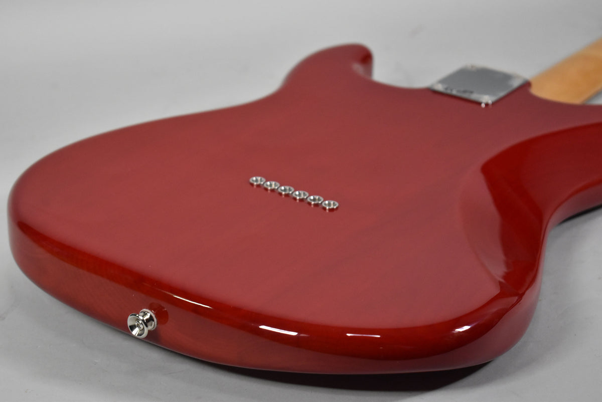 The back of a crimson red Stratocaster body, showing the string-through ferrules, output jack, and neck plate.