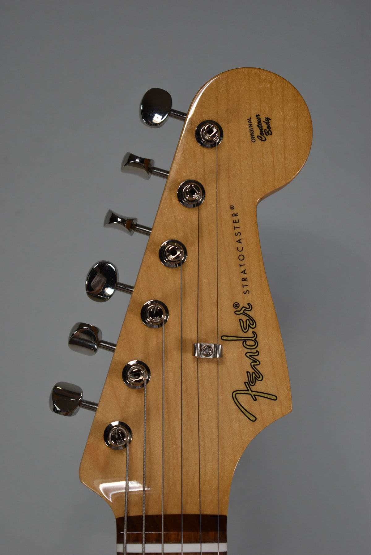 Close-up of the light wood headstock with six chrome tuners and a string tree, angled slightly to the left.