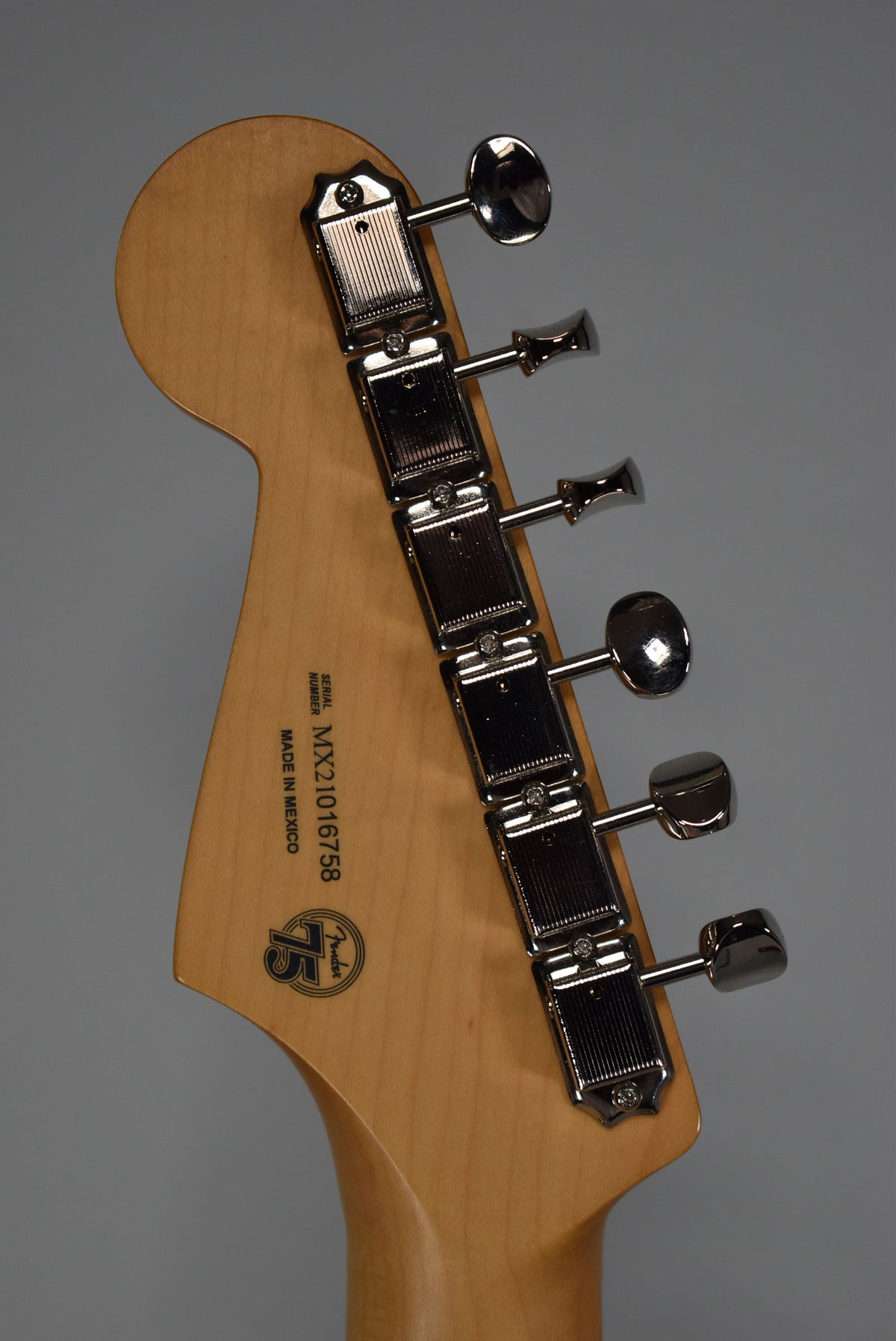 Rear view of the light wood headstock, showing six chrome tuners with ridged housings and oval buttons.