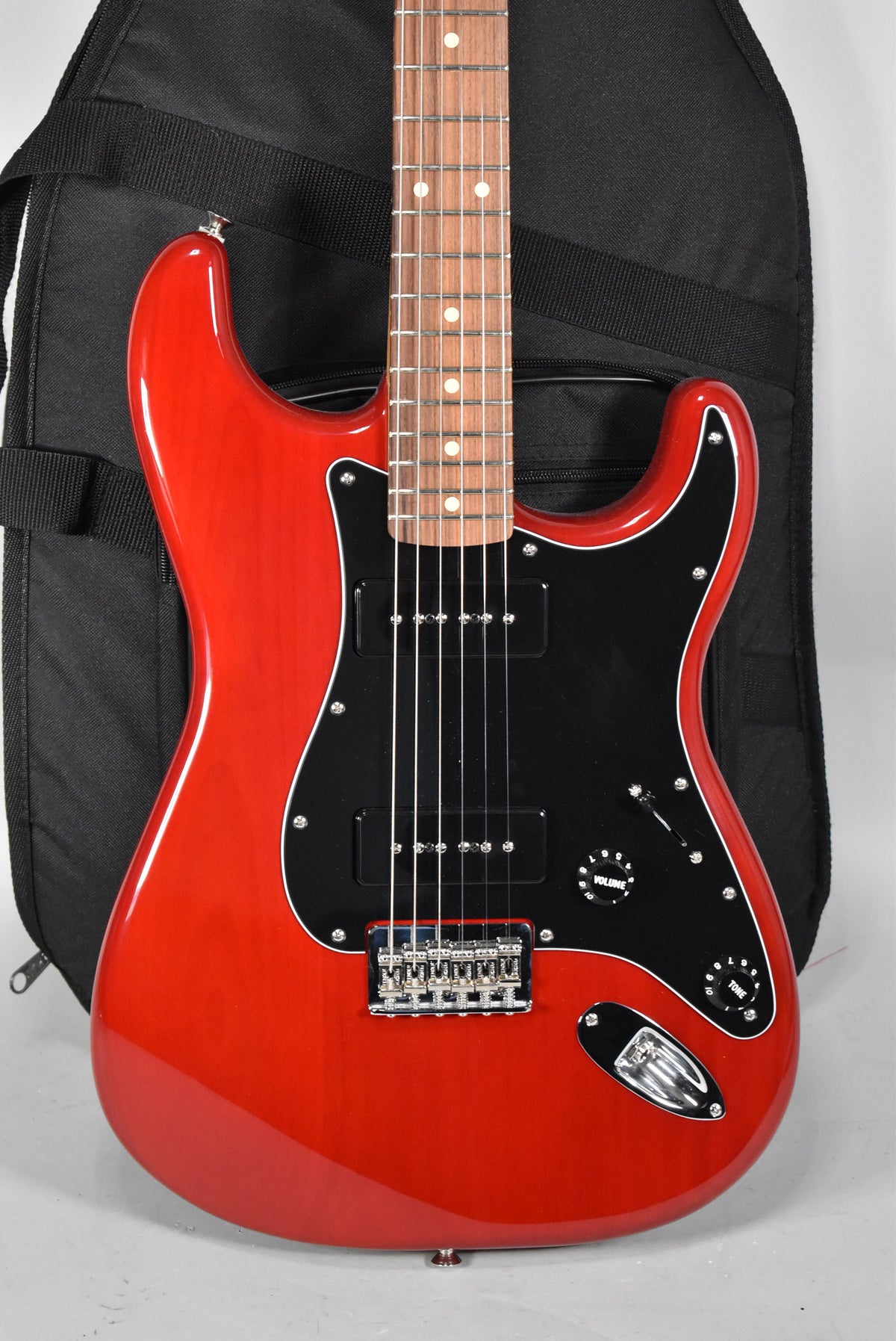 Crimson red Stratocaster, angled from above, showing the glossy body, black pickguard with two P90 pickups, and a rosewood fretboard.
