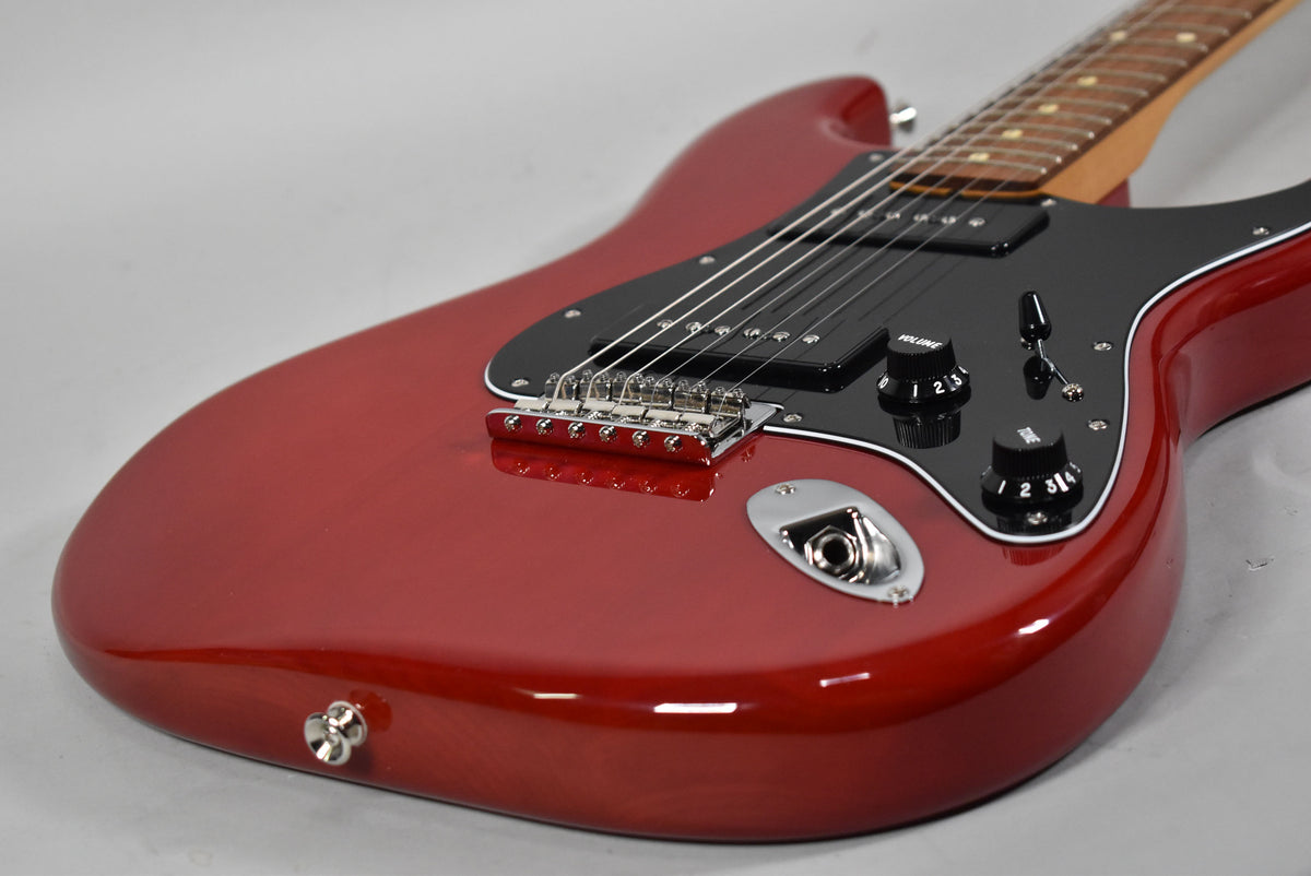 The crimson red Stratocaster body, with a glossy finish, features a black pickguard, two black control knobs, and a chrome output jack.