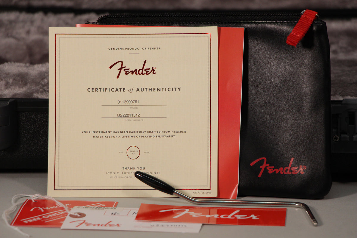Close-up of the guitar's accessories: a certificate of authenticity, a black tremolo arm, and various tags and papers, all new.